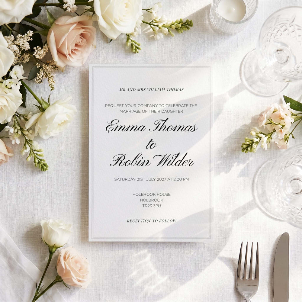 Foil-pressed wedding invitation styled on a linen tablescape with roses