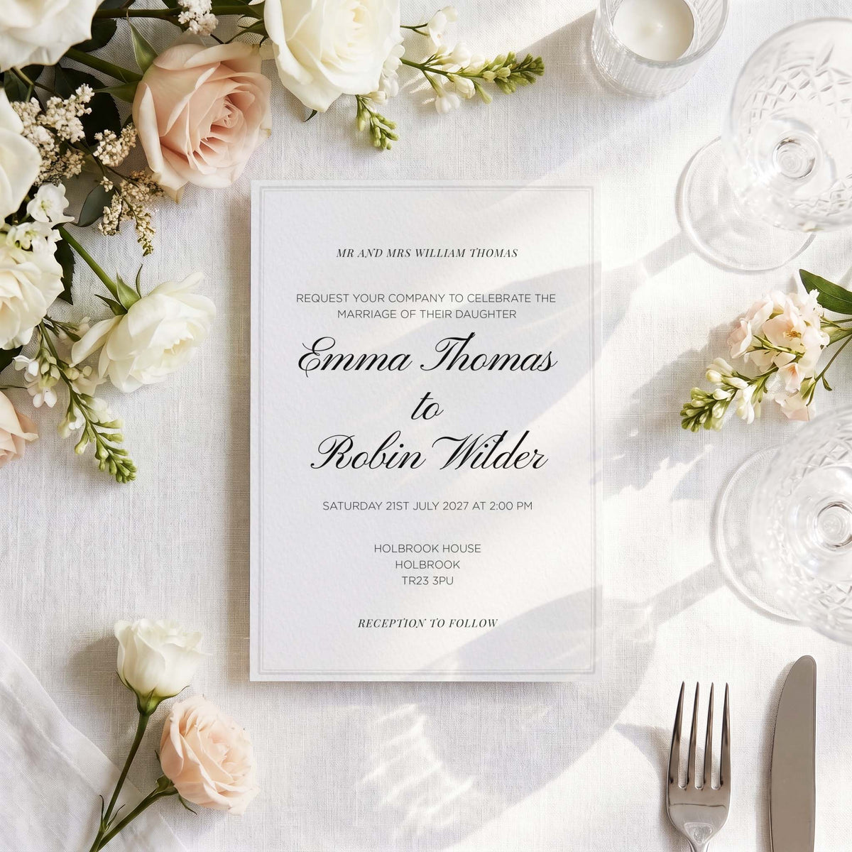 Foil-pressed wedding invitation styled on a linen tablescape with roses