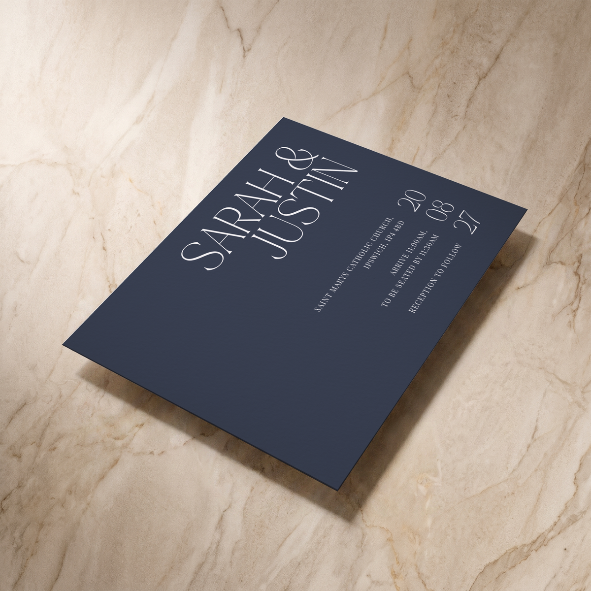 Typeface wedding invitation in navy, shown at an angle, designed and printed in Suffolk