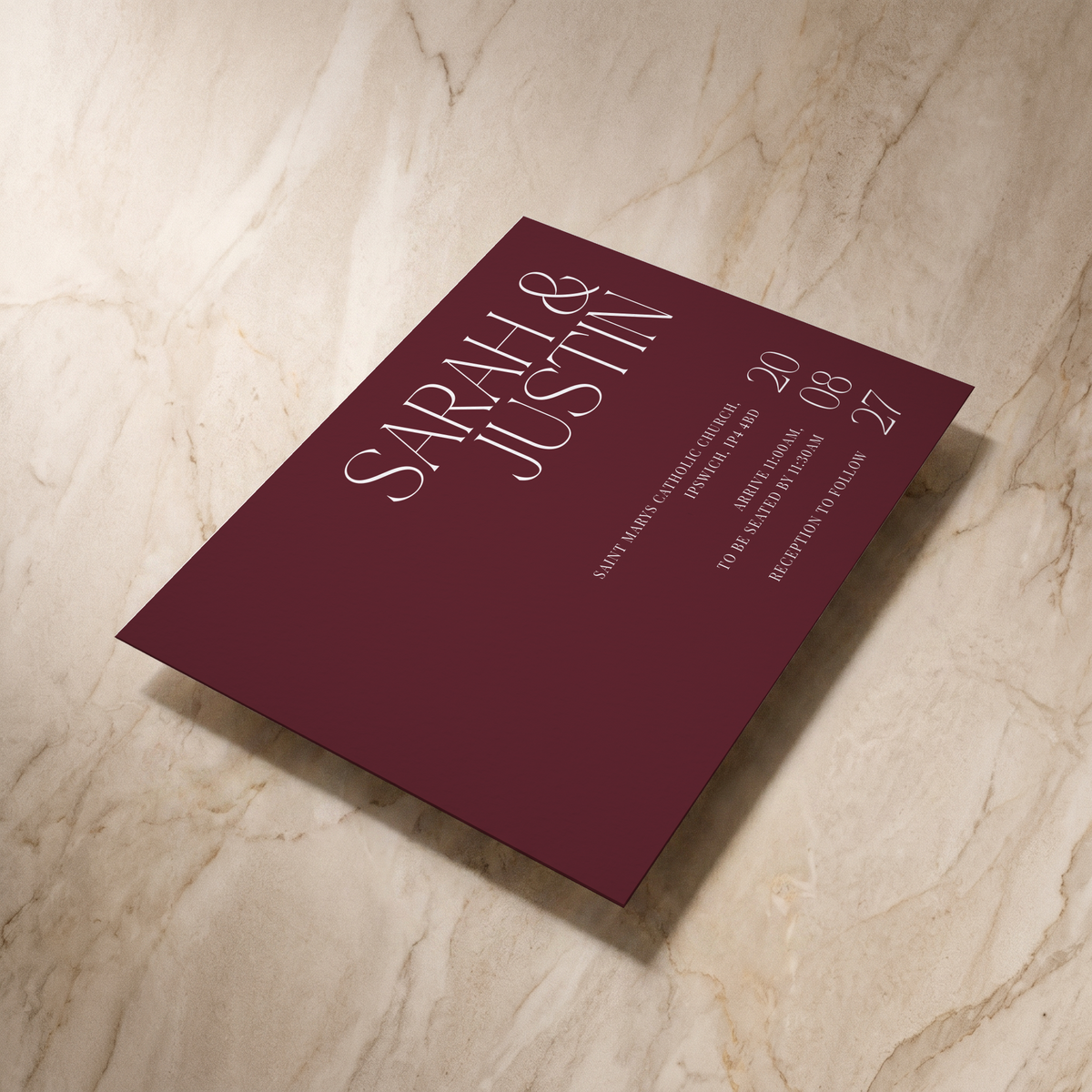 Typeface wedding invitation in maroon, shown at an angle, designed and printed in Suffolk