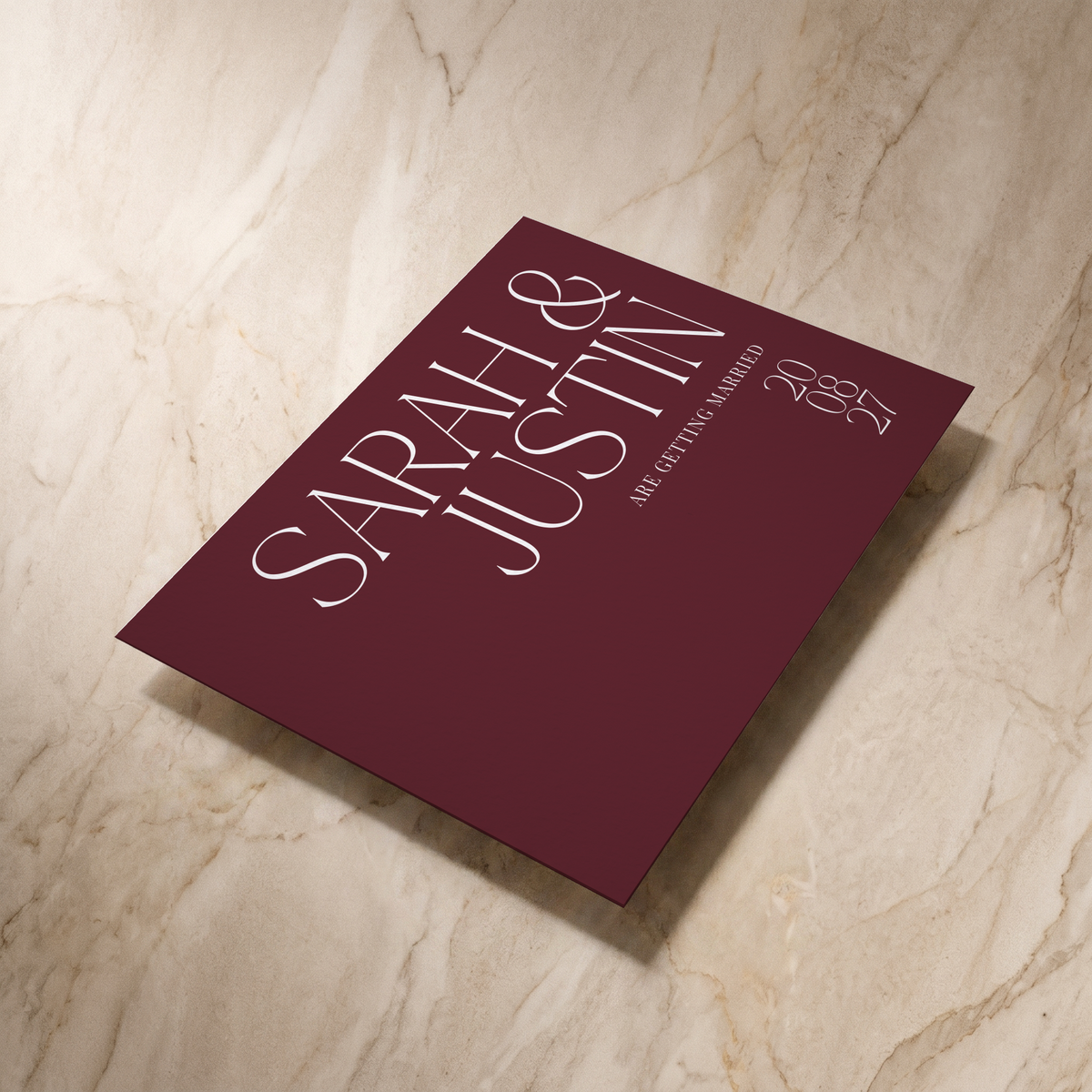 Typeface save the date card in maroon, shown at an angle, designed and printed in Suffolk